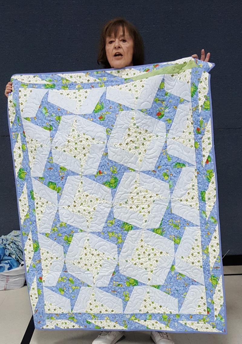 Elaine shows a completed Linus quilt that is an 
